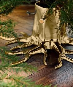 an octopus - like planter is sitting on the floor next to some pine branches