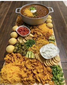 a platter filled with chips, salsa and dips on top of a wooden table