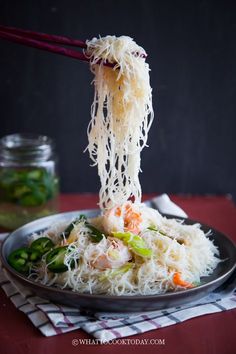 someone is eating noodles with chopsticks on a plate and fork in the air