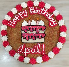 a birthday cake with candles and flowers around it that says happy birthday april on the top