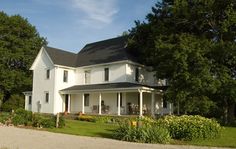 a large white house sitting on top of a lush green field