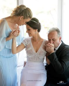 two women and a man standing next to each other with their hands on their chest