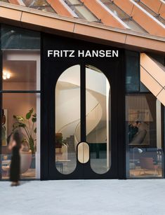 a man walking past a store front with large glass doors and an open door that says frittz hansen