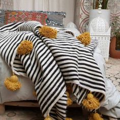 a black and white striped blanket with yellow pom poms