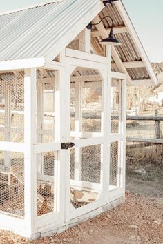 a small white chicken coop with a roof