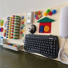 a computer keyboard sitting on top of a desk next to a wall mounted phone holder