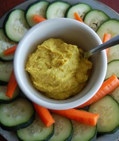 hummus and carrots on a plate with cucumbers