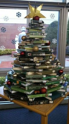 a christmas tree made out of books sitting in front of a window