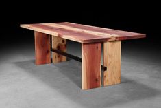 a wooden table sitting on top of a cement floor next to a black wall with writing underneath it