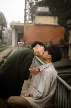 two people kissing each other on a bridge