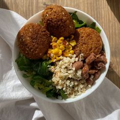 a white bowl filled with food on top of a wooden table next to a napkin