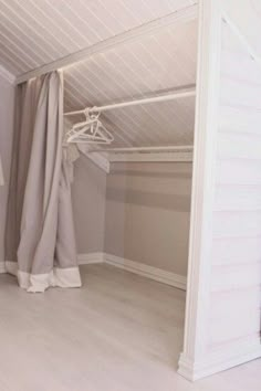 an empty room with some clothes hanging on the rack and curtains in front of it