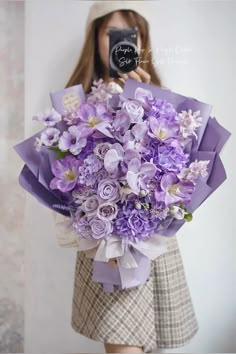 a woman holding a bouquet of purple flowers