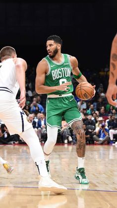 boston basketball player dribbling the ball while being guarded by an opponent in a game