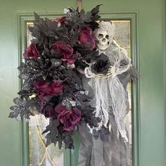 a skeleton is holding a bouquet of flowers in front of a green door with black and white decorations