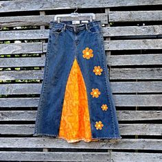 a pair of jeans with flower appliques on them hanging from a clothes line