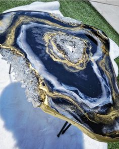 a large black and gold agate stone sitting on top of a green grass covered field