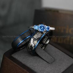 two wedding bands with blue topazs are sitting on a wooden stand in front of a book