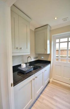 an empty kitchen with white cabinets and black counter tops is seen in this image from the doorway