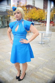 a woman in a blue dress is posing for the camera with her hands on her hips