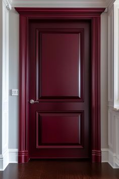 an empty room with a red door and wooden floors