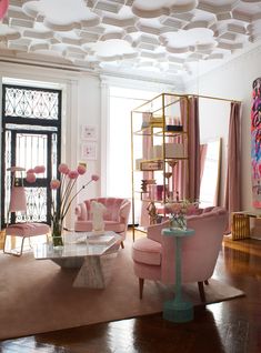 a living room filled with pink furniture and decor on top of a hard wood floor