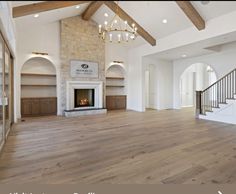 an empty living room with wood floors and a stone fireplace in the center is surrounded by arched doorways