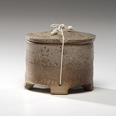 a brown and white ceramic container with rope on top