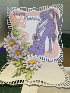 a birthday card with a shoe and flowers on the front, sitting on top of a table