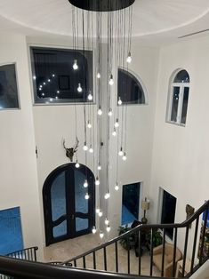 a spiral staircase with lights hanging from it's sides and an open door leading to the second floor