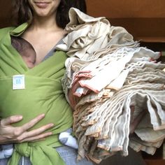 a woman holding a baby wrapped in cloths and wearing a green wrap around her neck