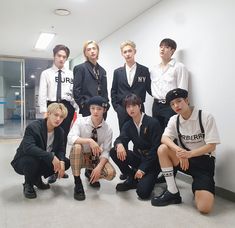 a group of young men sitting next to each other in front of a white wall