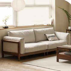 a living room with a couch and coffee table in front of a window that has blinds on the windowsill