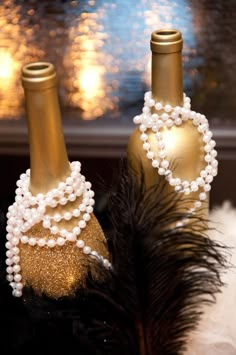 two wine bottles decorated with pearls and feathers