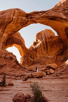 a person standing in front of a large rock formation with an arch over it's entrance