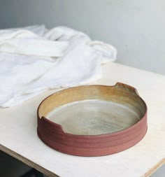 a bowl sitting on top of a wooden table next to a white towel and cloth