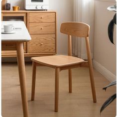 a wooden chair sitting in front of a microwave oven next to a table with a cup on it