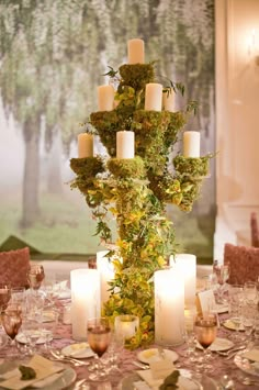 a tall vase filled with candles sitting on top of a table covered in plates and napkins