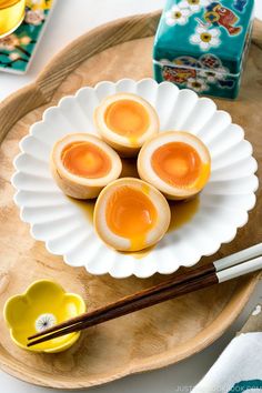 three hard boiled eggs on a plate with chopsticks