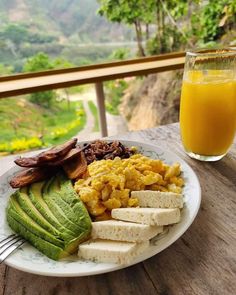 a plate with eggs, avocado and toast on it next to a glass of orange juice