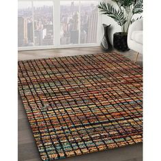 an area rug with multicolored squares on the floor in front of a window