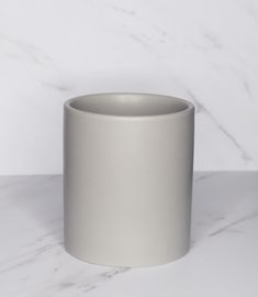 a silver cup sitting on top of a white counter next to a marble wall and floor