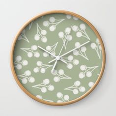 a green clock with white flowers and leaves on it's face, showing the time