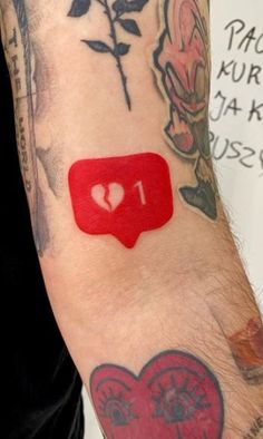 a person with tattoos on their arm has a red sticker in the shape of a heart