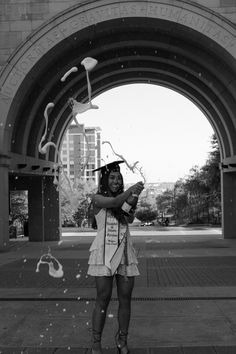 a woman in a graduation gown is throwing confetti into the air