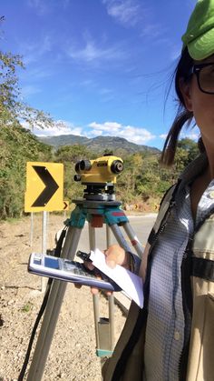 a woman standing next to a camera on top of a tripod with a map