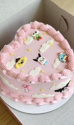 a pink cake with white frosting and cartoon characters on the top is in a box