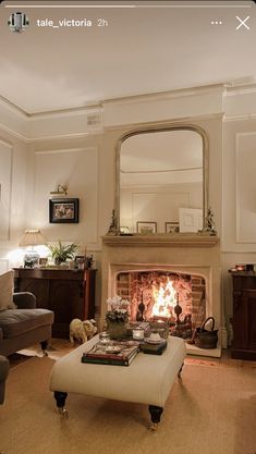 a living room filled with furniture and a fire place under a mirror on the wall