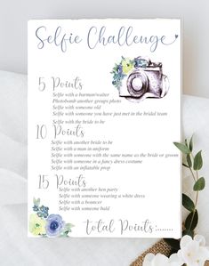 a sign that says selfie challenge on it with flowers and greenery next to it