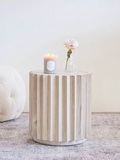 a small vase with a flower on it next to a candle